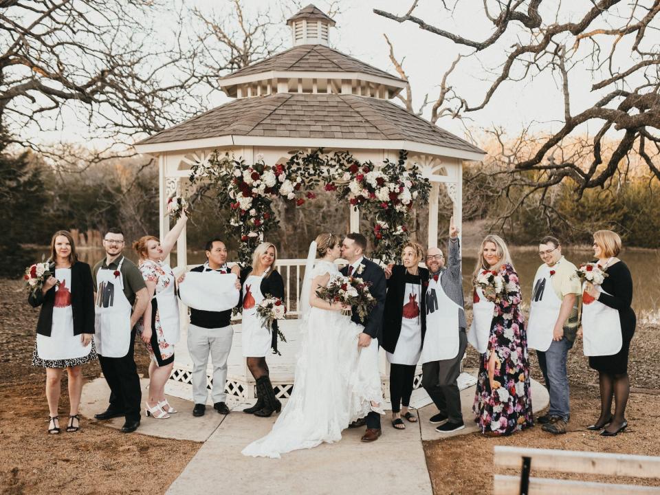 A bridal party poses with a kissing bride and groom.