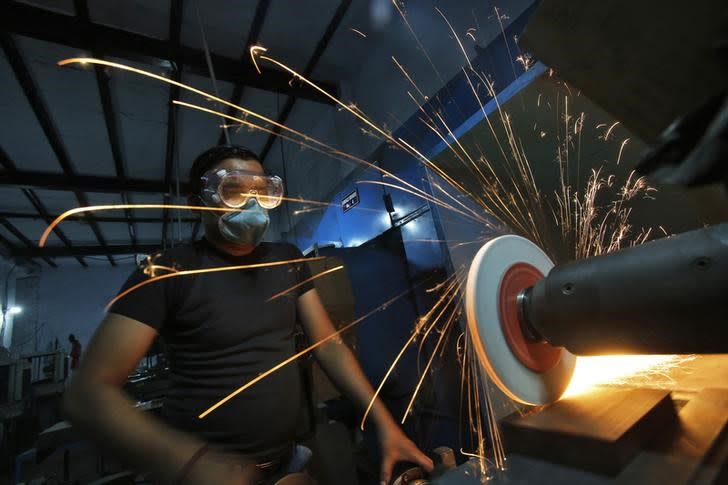A worker operates a lathe machine as he makes a steel cutter at a manufacturing unit in Noida, on the outskirts of New Delhi November 3, 2014. REUTERS/Anindito Mukherjee/Files