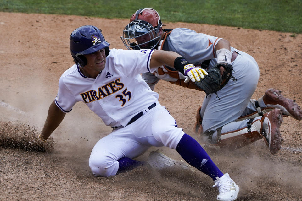 East Carolina's Bryson Worrell scores past Texas catcher Silas Ardoin on a hit by Josh Moylan during the seventh inning of an NCAA college super regional baseball game Friday, June 10, 2022, in Greenville, N.C. (AP Photo/Chris Carlson)