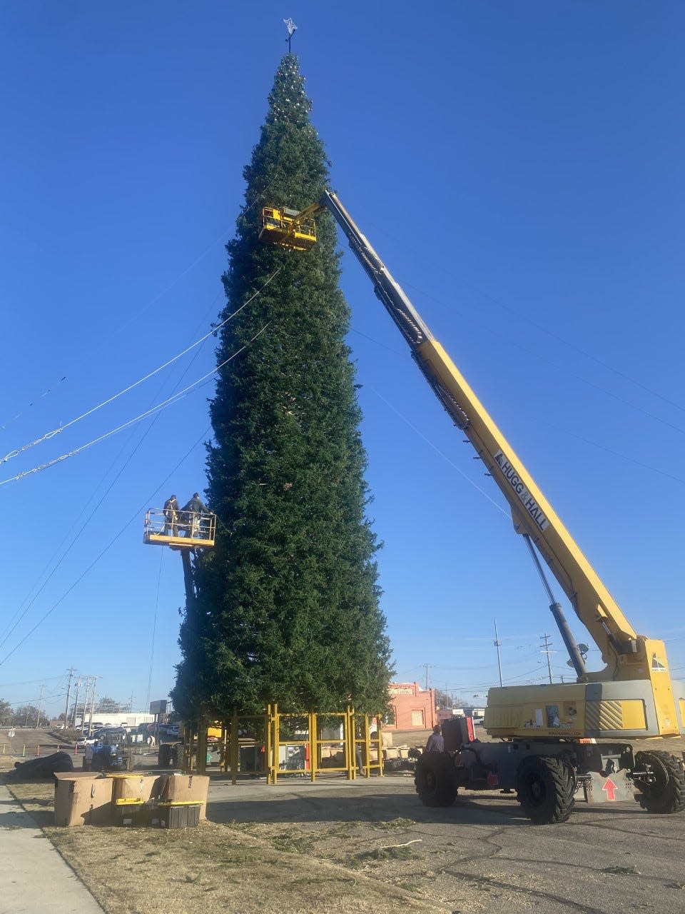 Using boom lifts, crews decorate the 140-foot-tall "world's largest fresh-cut Christmas tree" in downtown Enid.
