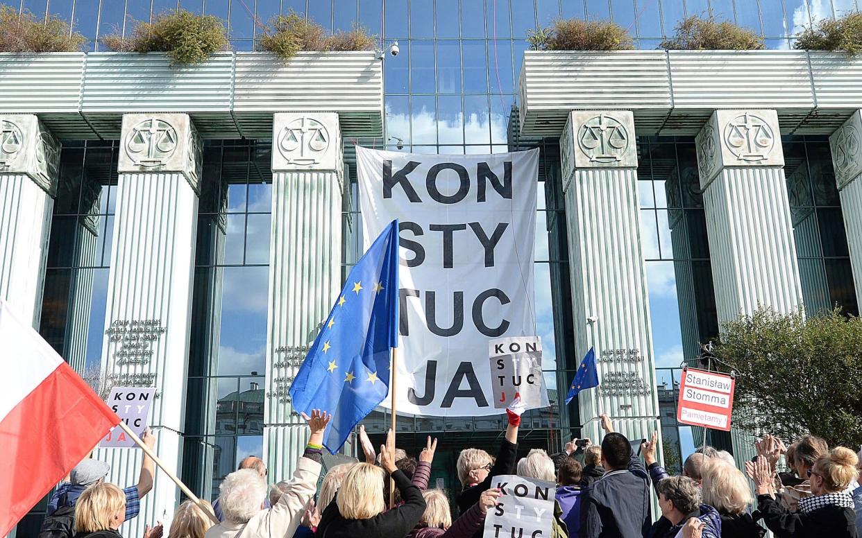 Government opponents in Warsaw with signs reading 'Constitution' protest an overhaul of the justice system - AP