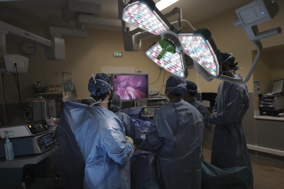 Medical staff work on the surgery of Lolita Andela at Bichat Hospital, AP-HP, in Paris, Wednesday, Dec. 2, 2020. After multiple false dawns, they scarcely dare believe that their Paris hospital, no longer overwhelmed by COVID-19 patients, is now once again able to perform their weight-reducing intestinal tucks. When the epidemic was burning through hospital resources, the women's operations were pushed back time and again. (AP Photo/Francois Mori)