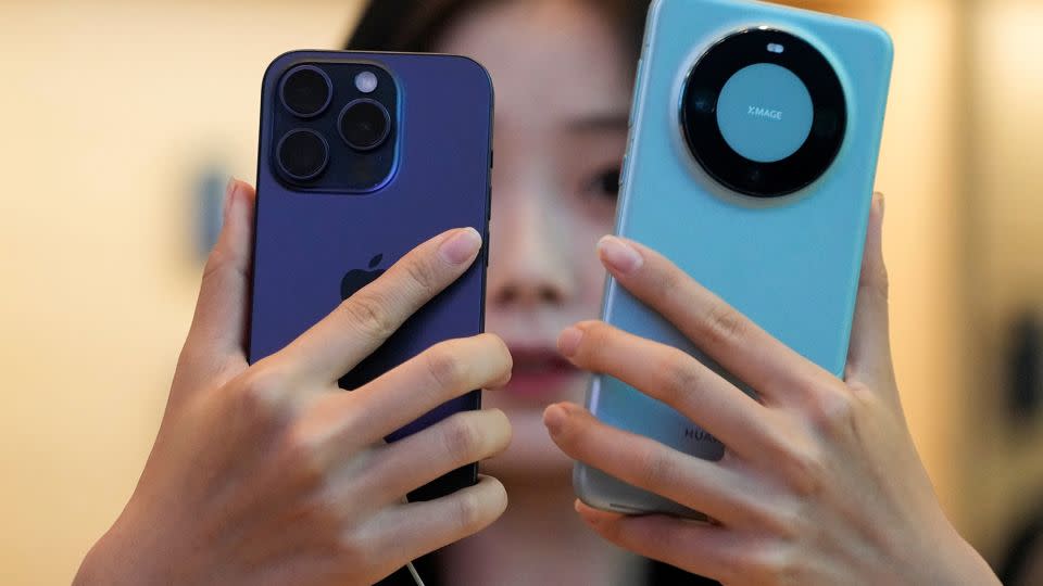 A woman looks at a new iPhone 15 Pro and a Huawei Mate 60 Pro as Apple's new iPhone 15 officially goes on sale across China, at an Apple store in Shanghai, China September 22, 2023. - ALY SONG/X01793/REUTERS