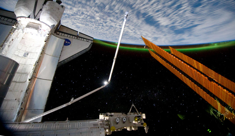 The Southern Lights or Aurora Australis ring planet earth as the docked space shuttle Atlantis' cargo bay (L) and the solar array panel of the International Space Station are seen July 14, 2011 in space. (NASA via Getty Images)