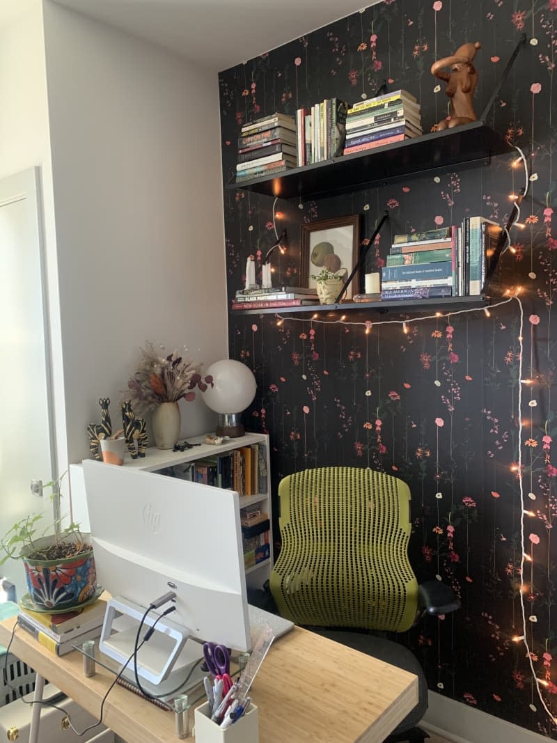 Office space with green Herman Miller office chair with a wall with string lights.