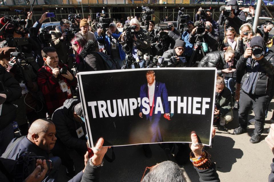 A woman holds up a poster as part of a protest in front of the courthouse ahead of former President Donald Trump's anticipated indictment on Monday, March 20, 2023, in New York. (AP Photo/Eduardo Munoz Alvarez)