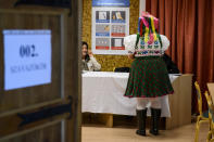 Sporting a folk costume Piroska Kovacsne Bablena takes over her ballot papers at the nationwide local elections in the village of Rimoc, Hungary, Sunday, Oct. 13, 2019. (Peter Komka/MTI via AP)