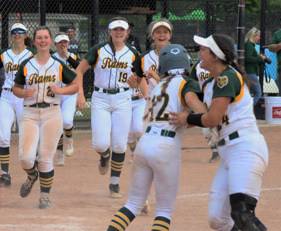 Flat Rock's softball team rushes to celebrate with Maddie Portis (12) after she drew a game-winning hit by pitch against New Boston Huron in the Division 2 District championship Saturday, June 4, 2022. It is the fourth straight District title for the Rams.