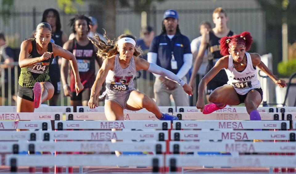 North Canyon's Rebekah-Jhade Garrett (right) and Hamilton's Kori Martin (center) go over the hurdles during the 100M Hurdles in the Open State Track and Field Championships at Mesa Community College on May 11, 2024.