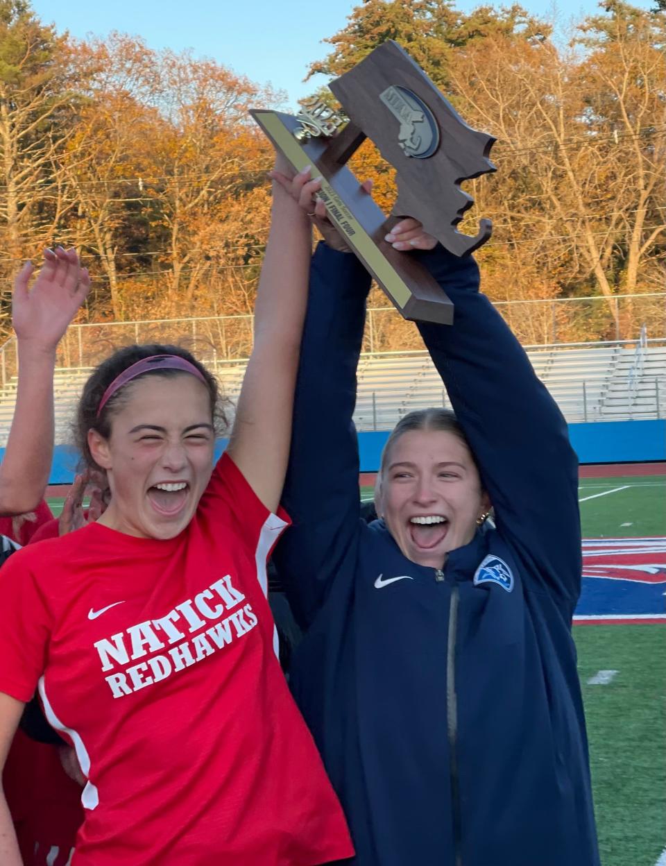 Natick captains Kaitlyn LeBrun, left, and Maya Schwab lift the Final Four trophy after the Redhawks defeated Concord-Carlisle on Nov. 12, 2023.