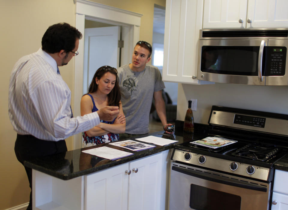 Realtor Steve Bremis (L) talks to house hunters Makayla Gavitt (C) and David Harris during an open house at a condominium unit in Somerville, Massachusetts. (Credit: Brian Snyder, REUTERS) 