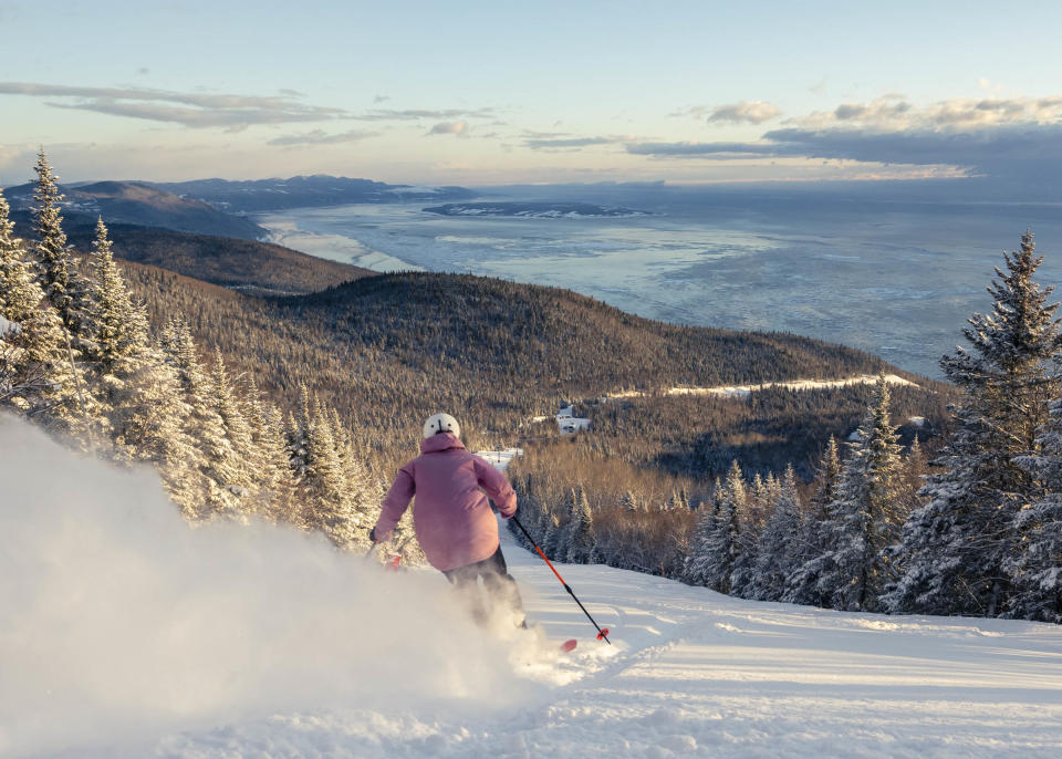 Woman skiing at Le Massif de Charlevoix with a beautiful view of the scenery below