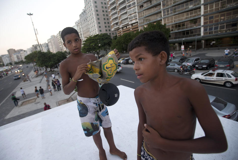 Elias, 14, left, and Lucas, 11, show their broken ball during a protest demanding better public services and against the upcoming World Cup soccer tournament in Rio de Janeiro, Brazil, Saturday, Jan. 25, 2014. Last year, millions of people took to the streets across Brazil complaining of higher bus fares, poor public services and corruption while the country spends billions on the World Cup, which is scheduled to start in June. (AP Photo/Silvia Izquierdo)