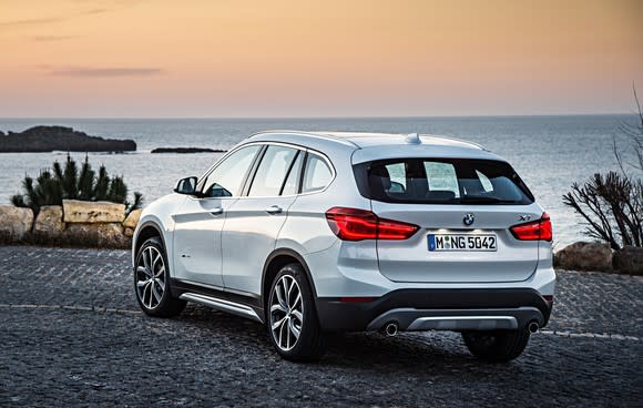 A white BMW X1, a small SUV, parked on a waterfront.