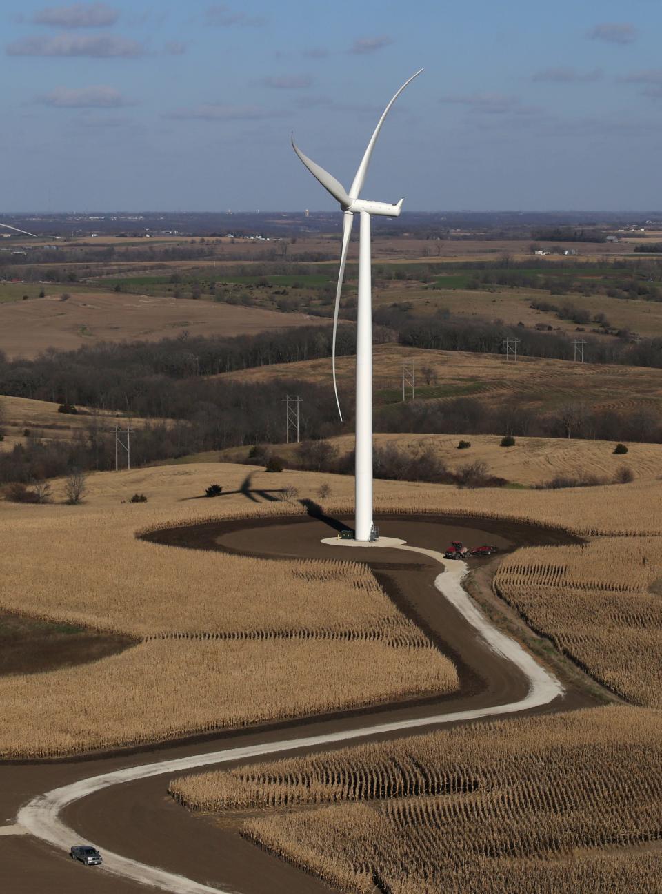 A truck winds along a gravel road and a tractor works in the field around a wind turbine as seen from the top of a turbine during a tour of a wind turbine unit on Thursday at the Macksburg wind project turbine farm in rural Macksburg.