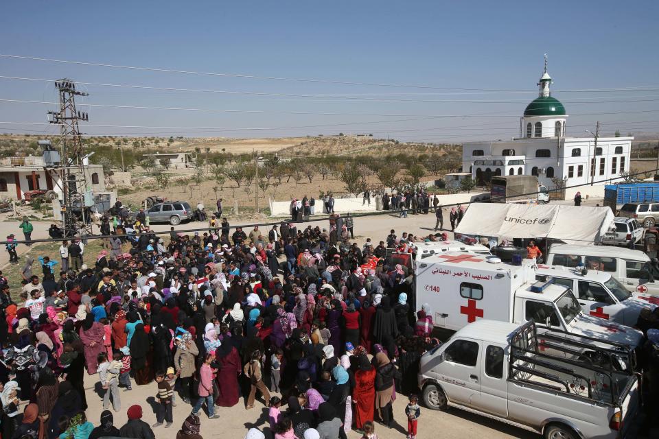 Lebanese and Syrian citizens gather to receive aid supplies, at the main square of Tfail village at the Lebanese-Syrian border, eastern Lebanon, Tuesday April 22, 2014. A Lebanese convoy of soldiers, clerics and Red Cross officials delivered aid Tuesday to a remote village near the Syrian border that was bombed by Syrian government aircraft and blocked by Lebanese militants fighting alongside President Bashar Assad’s forces in the civil war next door. Hezbollah fighters have been patrolling the area on the Lebanese side and fighting has flared up inside Syria, cutting Tfail’s residents off from all sides for months. (AP Photo/Hussein Malla)