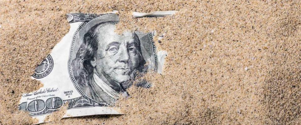 100 dollar bill buried in the sand