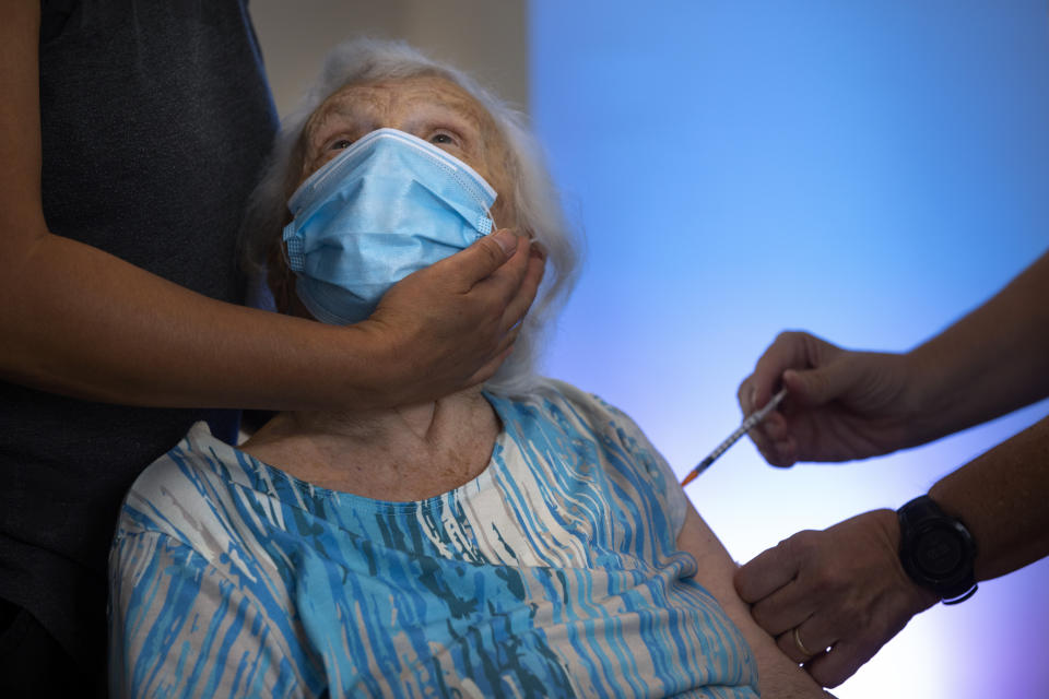 Blossom Koppelman, 86, receives a third Pfizer-BioNTech COVID-19 vaccine from a Magen David Adom national emergency service volunteer, at a private nursing home, in Netanya, Israel, Sunday, Aug. 1, 2021. Israeli health authorities began administering coronavirus booster shots on Friday to people over 60 who've already received both doses of a vaccine, in a bid to combat a recent spike in cases. (AP Photo/Oded Balilty)