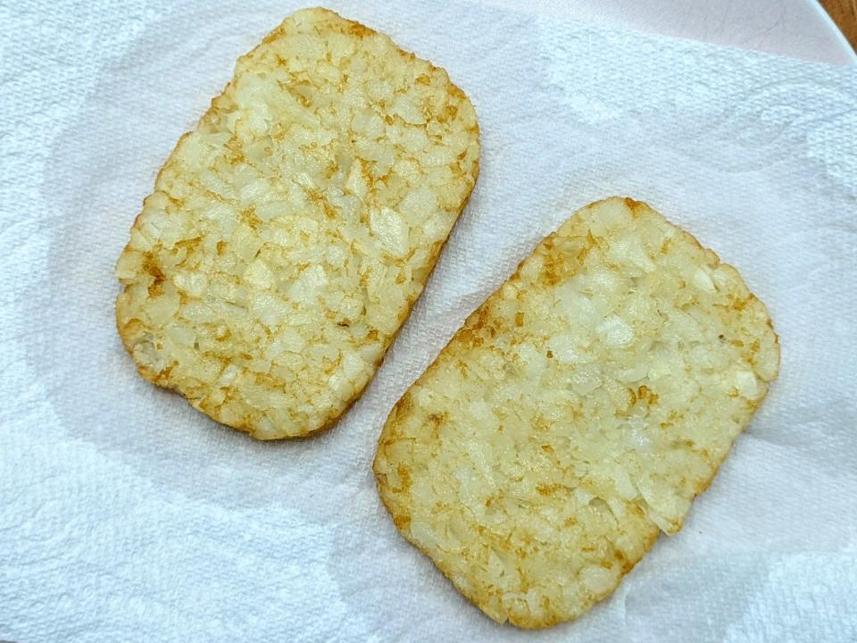 two hash brown patties on a paper towel on a plate