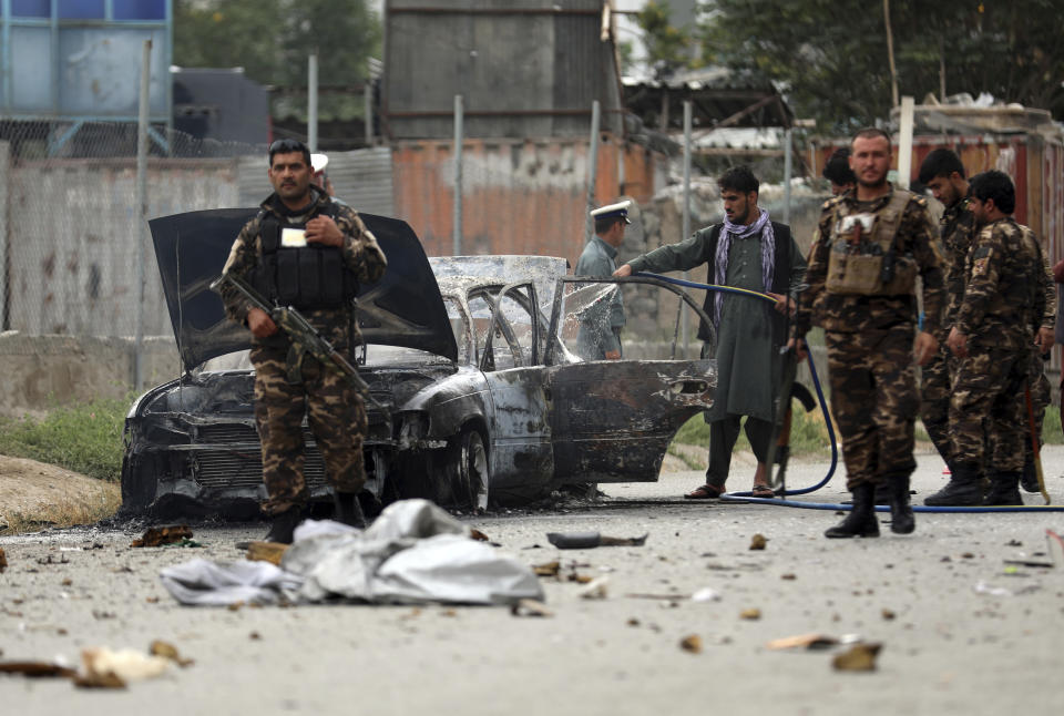 Security personnel inspect a damaged vehicle which was firing rockets in Kabul, Afghanistan, Tuesday, July 20, 2021. At least three rockets hit near the presidential palace on Tuesday shortly before Afghan President Ashraf Ghani was to give an address to mark the Muslim holiday of Eid-a-Adha. (AP Photo/Rahmat Gul)