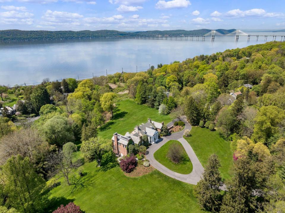 a mansion overlooking the hudson river with a bridge in the distance