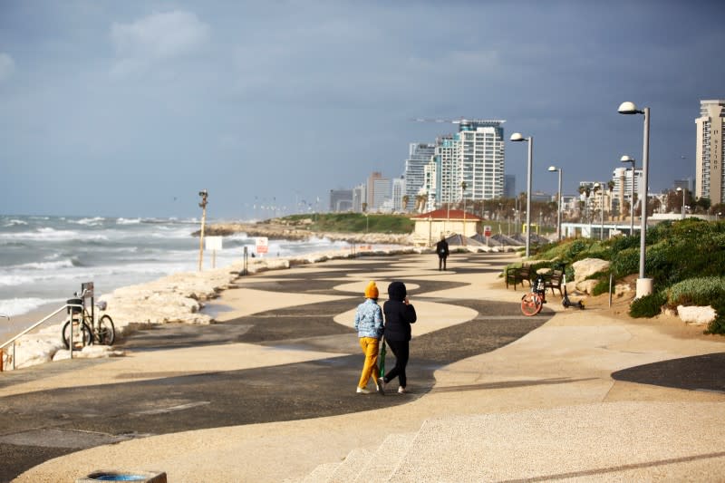 FILE PHOTO: Women walk by the shore of the Mediterranean Sea in Tel Aviv