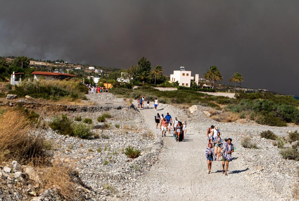 希臘人氣度假勝地羅得斯島（Rhodes）遭受野火肆虐，數千名觀光客頂著高溫、拉著行李，徒步撤離好幾公里。（路透社）