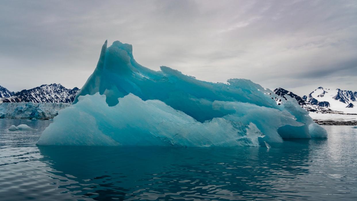  A large light blue glacier floating in the ocean 