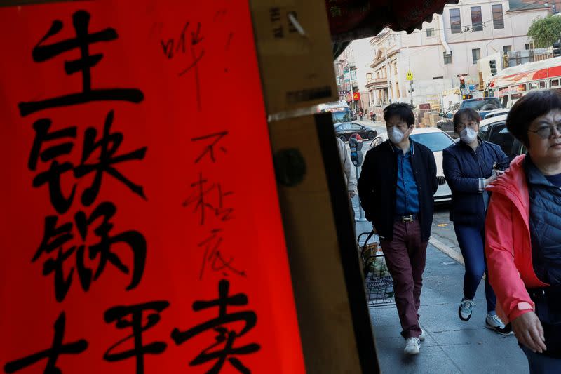 People wear face masks walking through the Chinatown section of San Francisco, California