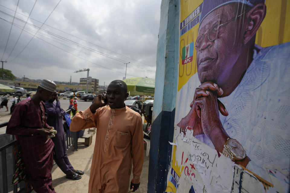 People walk past posters of Presidential candidate Bola Tinubu of the All Progressives Congress in Lagos, Nigeria Monday, Feb. 27, 2023. Each of the three frontrunners in Nigeria's hotly contested presidential election claimed they were on the path to victory Monday, as preliminary results trickled in two days after Africa's most populous nation went to the polls. (AP Photo/Sunday Alamba)