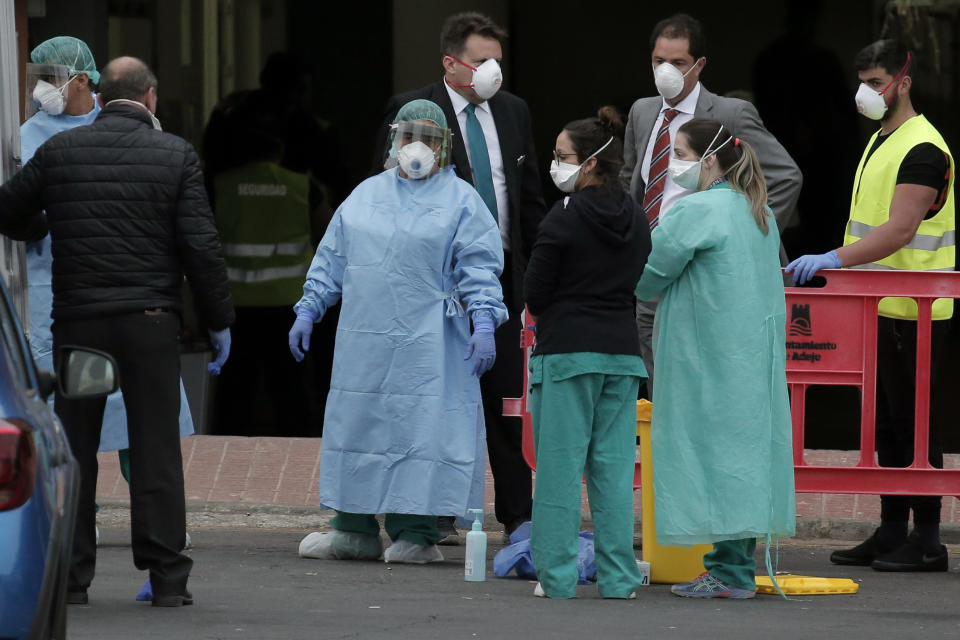 Health personnel wearing protection clothing look on as guests prepare to leave the H10 Costa Adeje Palace hotel in La Caleta, in the Canary Island of Tenerife, Spain, Friday Feb. 28, 2020. Some guests have started to leave the locked down hotel after undergoing screening for the new virus that is infecting hundreds worldwide. (AP Photo/Joan Mateu)