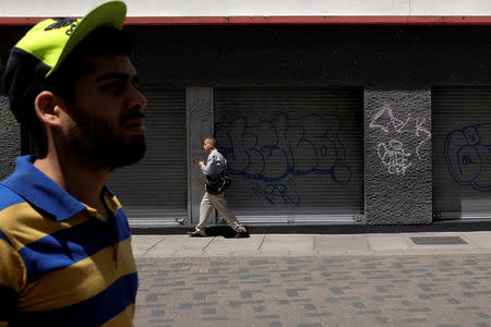 People walk past closed stores in Caracas, Venezuela August 17, 2018. REUTERS/Marco Bello