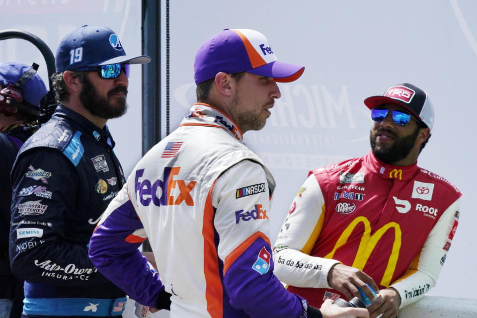 Denny Hamlin, center, talks with Martin Truex Jr., left, and Bubba Wallace before driver introductions at the NASCAR Cup Series auto race at Michigan International Speedway, Sunday, Aug. 22, 2021, in Brooklyn, Mich. (AP Photo/Carlos Osorio)