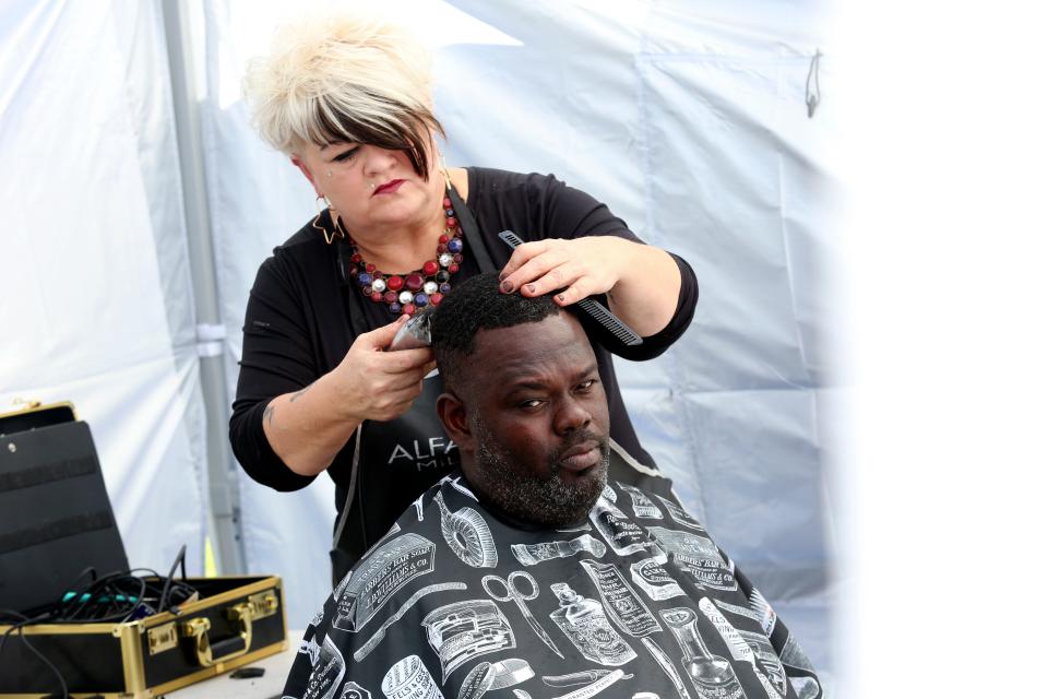 Missy Fountain, of Arcadia, cuts the hair of Johnny Faucette, of Naples, on Sunday, Oct. 16, 2022, in Immokalee, Fla., under a tent near a church service for Lilly Bass Church of God in Unity. “I’ve been going to this church for years,” Faucette said. The congregation of Lilly Bass, anywhere from 25-50 people, now worships near the ashes of what once held their pentecostal church that burned down on Sept. 16, 2022. 