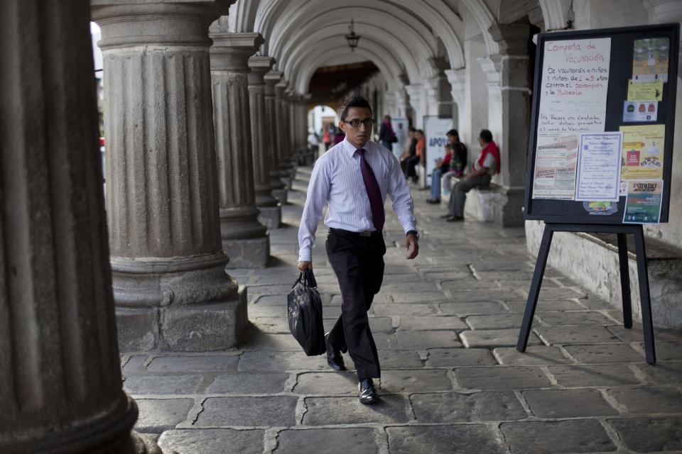 In this Nov. 14, 2013 photo, a man walks past the city council in Antigua, Guatemala. Earlier in November, hundreds marched to demand the appointment of a new city administration, saying they were tired of water being cut off, trash not being picked up and stoppages on public transportation. (AP Photo/Luis Soto)