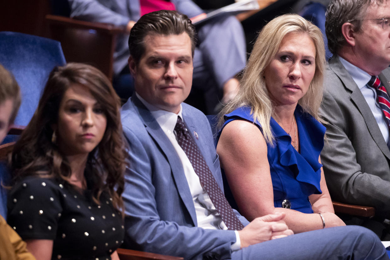 Reps. Lauren Boebert, Matt Gaetz and Marjorie Taylor Greene, seated together, look to their right while refusing to wear face masks in a committee hearing.