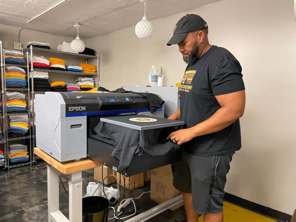 Miki Merritt, founder of apparel company 573 Tees, prints a T-shirt at his store in Columbia, Missouri.