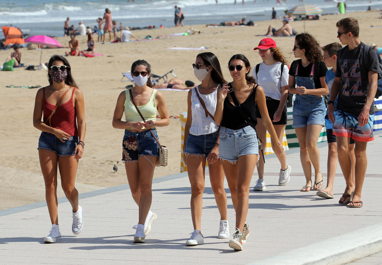 People wear face masks as they walk near the beach in Biarritz, southwestern France, Tuesday, July 21, 2020. Face masks are now obligatory in France's supermarkets, shopping malls, banks, stores, and indoor markets, to curb worrisome signs that the coronavirus is making inroads again. (AP Photo/Bob Edme)