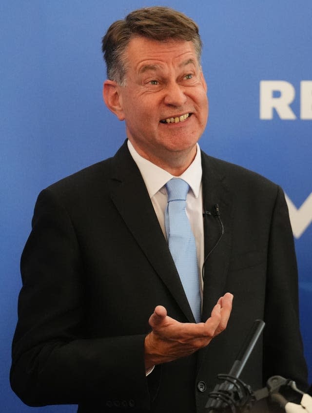 A man in a dark suit and a pale blue tie