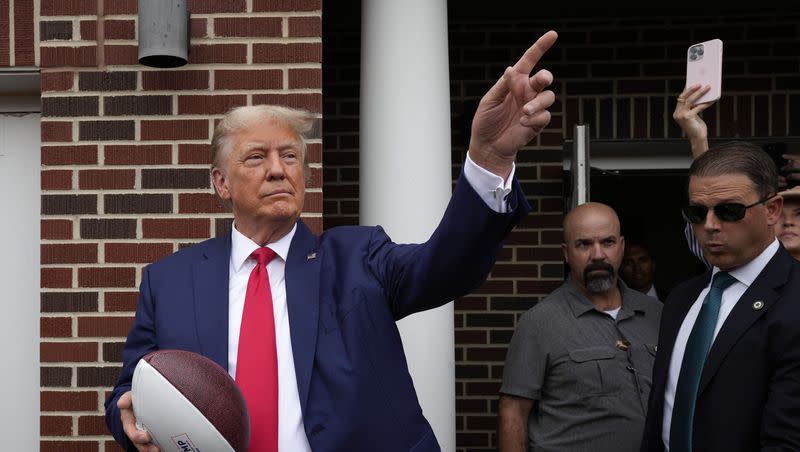 Former President Donald Trump holds a football before throwing it to the crowd during a visit to the Alpha Gamma Rho, an agricultural fraternity, at Iowa State University before a college football game between Iowa State and Iowa on Saturday, Sept. 9, 2023, in Ames, Iowa.