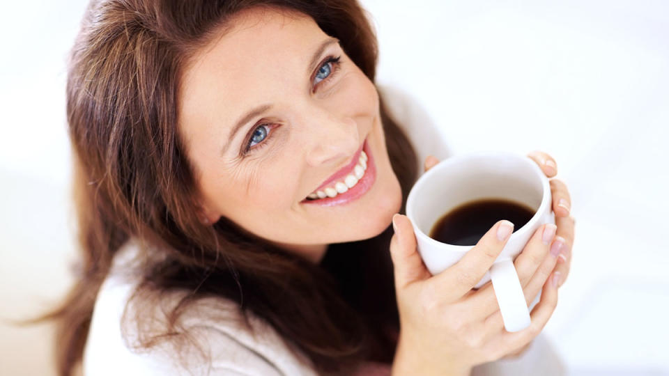 Smiling woman holding a mug of black coffee for weight loss