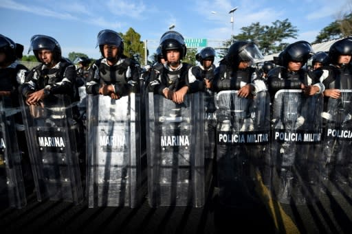 Mexican armed forces stand guard as Central American migrants, travelling in a caravan to the US, wait to cross the international bridge that connects Tecum Uman, Guatemala, with Ciudad Hidalgo, Mexico, on January 20, 2020