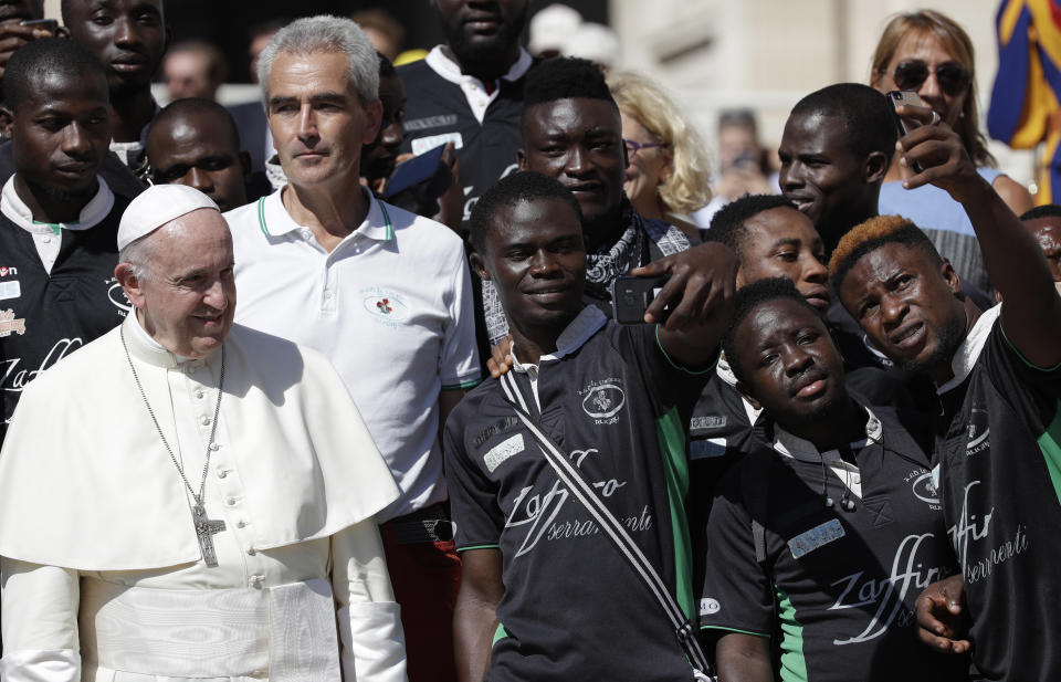 Pope Francis poses with members of a rugby team formed by refugees at the end of his general audience in St. Peter's Square at the Vatican Wednesday, Sept. 12, 2018. (AP Photo/Alessandra Tarantino)