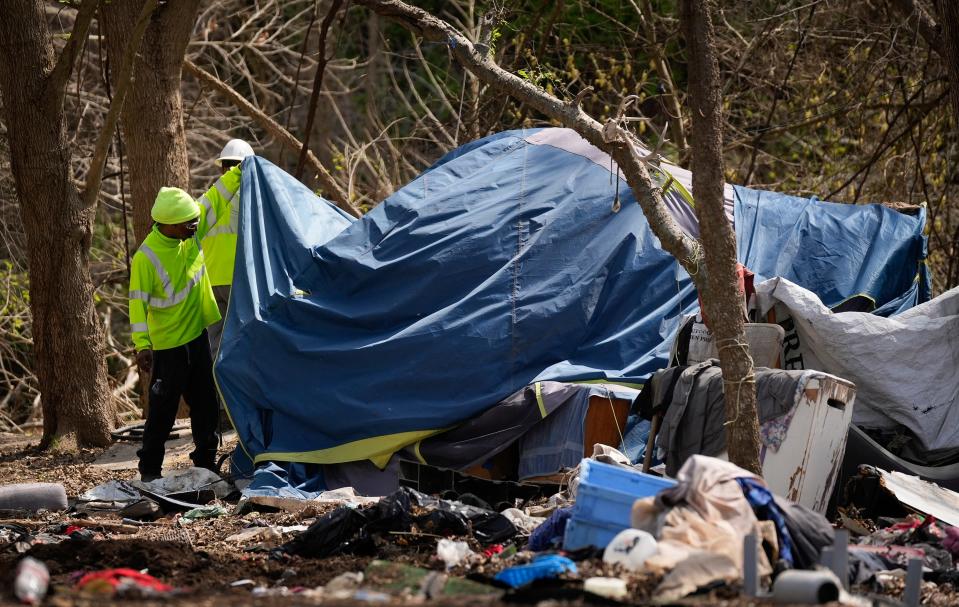 Austin Resource Recovery workers look at a tent during a sweep of a homeless camp in a wooded area off Brandt Road near Onion Creek Monday March 4, 2024. Residents said they weren't given any advance warning, just a few minutes to grab whatever belongings they could save before everything else was hauled away in garbage trucks.