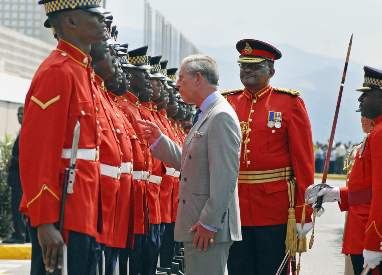 FILE - Britain's Prince Charles, center, inspects an honor guard upon his arrival at Victoria Pier in Kingston, Jamaica, Wednesday, March 12, 2008. For many countries in the Commonwealth, a group mostly consisting of former members of the British Empire, Charles’ coronation is seen with apathy at best, hostility at worst, a painful reminder of oppression and colonialism’s bloody past. (Collin Reid, Pool Photo via AP, File)