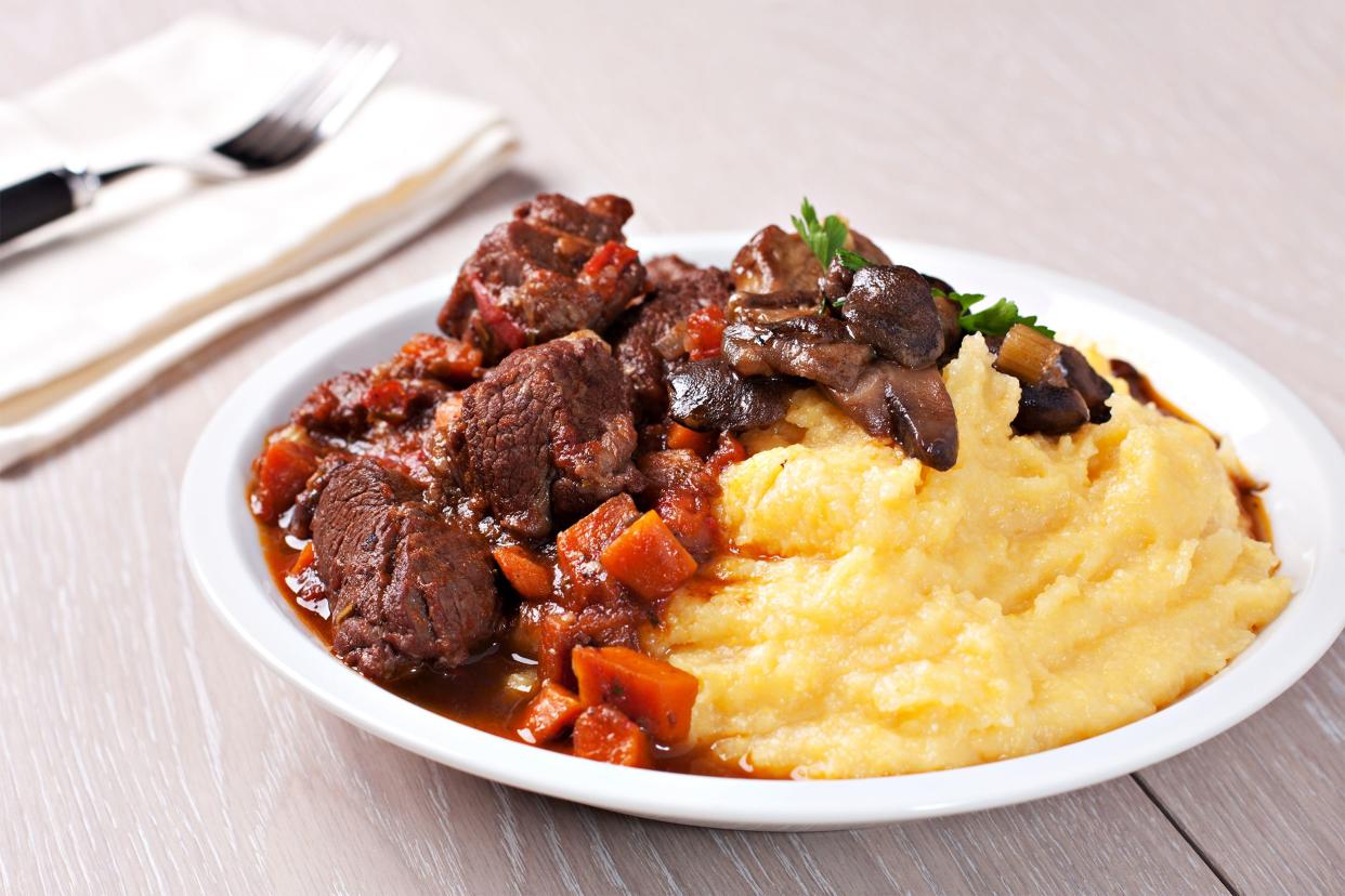 Beef Ragu With Polenta on a white plate on a white washed wood table