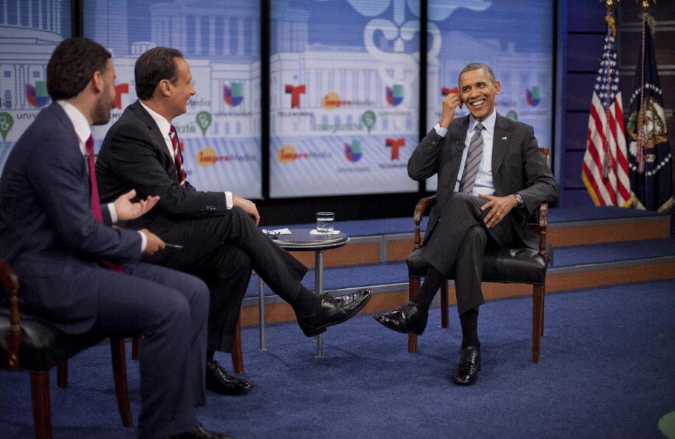 President Barack Obama adjusts his earpiece during a town hall event with television hosts Jose Diaz Balart and Enrique Acevedo, far left, at the Newseum in Washington, Thursday, March 6, 2014. The event was broadcast in both English and Spanish languages and the earpiece provided the English translation for the question asked about the importance of the benefits of the Affordable Care Act for Hispanic community. (AP Photo/Pablo Martinez Monsivais)