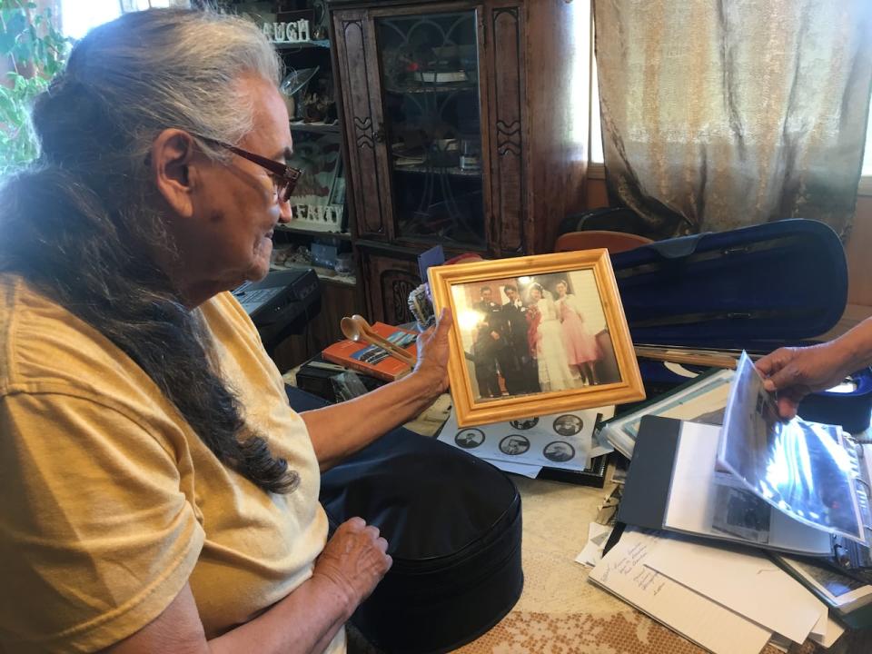 Dorothy Beaulieu with her wedding picture in front of the church in Fort Resolution, N.W.T. She plays the spoons while her husband Angus plays the fiddle.