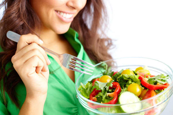 Close-up of pretty girl eating fresh vegetable salad