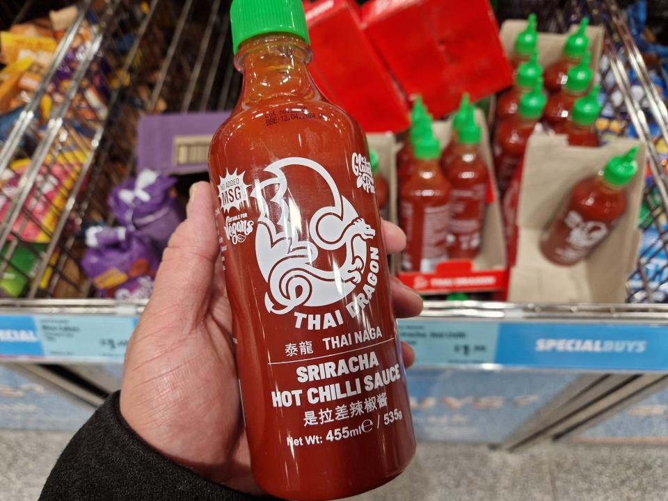 The writer holds a bottle of Sriracha